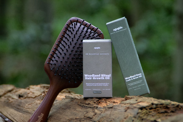 The Complete Growth Ritual: Root Ritual sandalwood scalp brush with Woodland Ritual and Woodland Gaze boxes on a forest log