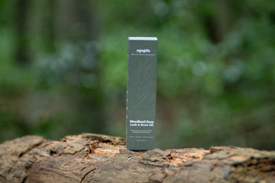 Woodland Gaze lash and brow oil box on a fallen log in a forest
