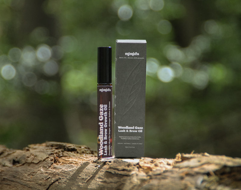 Woodland Gaze lash and brow growth oil tube beside its box on a forest log