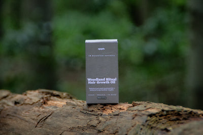Woodland Ritual Hair Growth Oil box on a fallen log in a forest