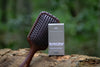 The Woodland Set: Root Ritual sandalwood scalp brush and Woodland Ritual Hair Growth Oil box on a forest log