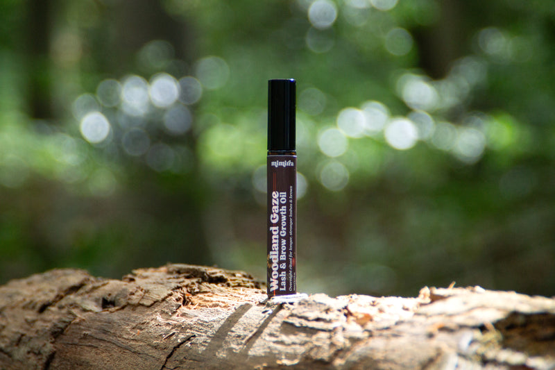 Woodland Gaze lash and brow growth oil tube on a log in a sunlit forest