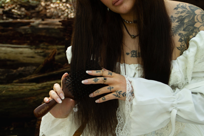 Woman with long dark hair using the Root Ritual sandalwood scalp brush
